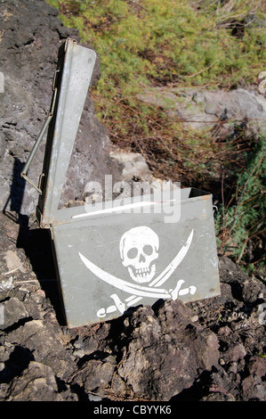 Geocache-Container mit Piratenschädel-Design, versteckt in felsigem Gelände auf einem Trail auf den Azoren, Portugal. Stockfoto