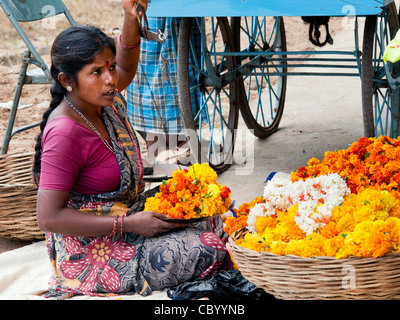 Indische Frau Ringelblumen für die Herstellung von Girlanden auf einer indischen Straße zu verkaufen. Puttaparthi, Andhra Pradesh, Indien Stockfoto