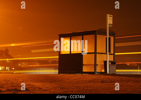 Bushaltestelle in der Nacht mit Lichtspur bis zur nächsten Bushaltestelle Stockfoto