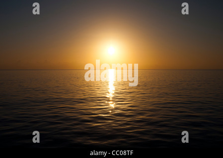 Die Sonne nähert sich den Horizont an einem sehr klaren und ruhigen Tag über dem Wasser. Aufgenommen am Swains Reef am südlichen Ende des Great Barrier Reef an der Küste von Queensland, Australien. Stockfoto