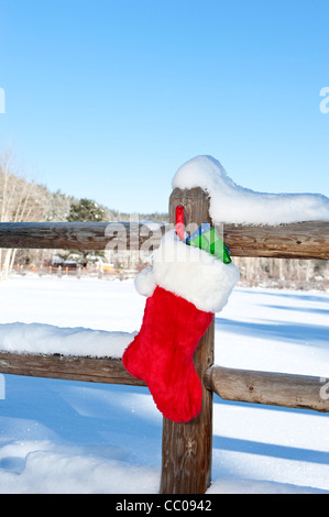 Ein Weihnachts-Strumpf gefüllt mit präsentiert an einem Holzzaun in einer Wildnis Resort Berg hängen. Stockfoto