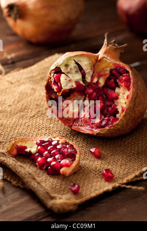 Granatapfel mit Samen auf Jute und Holz Stockfoto