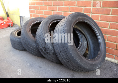 vier Teil getragen alte gebrauchte Reifen liegen außerhalb einer Garage in London-England-UK-Vereinigtes Königreich Stockfoto