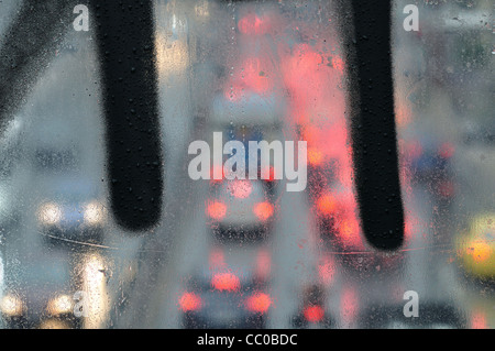 Regentropfen Makro auf Glas Überführung Oberfläche und verschwommene Stadt Ampel. Stockfoto