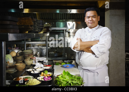 Porträt des erwachsenen Menschen bei der Arbeit als Koch in der Küche ein asiatisches Restaurant, posiert mit Arme gekreuzt Stockfoto