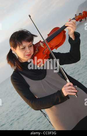 junges Mädchen beim spielt die Violine am Meer Stockfoto