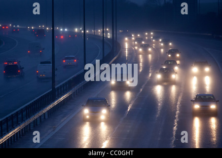 Auto und Verkehr auf einem nassen Abend auf Großbritannien Autobahn zu regnen. Autofahren in gefährlichen winterlichen Bedingungen. Stockfoto