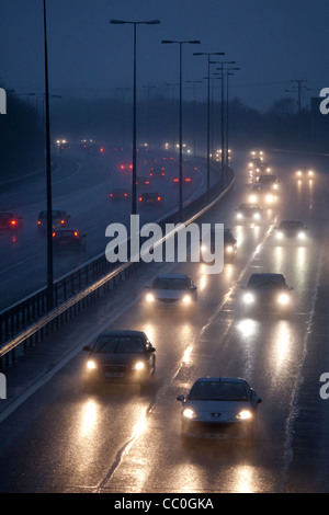 Auto und Verkehr auf einem nassen Abend auf Großbritannien Autobahn zu regnen. Autofahren in gefährlichen winterlichen Bedingungen. Stockfoto