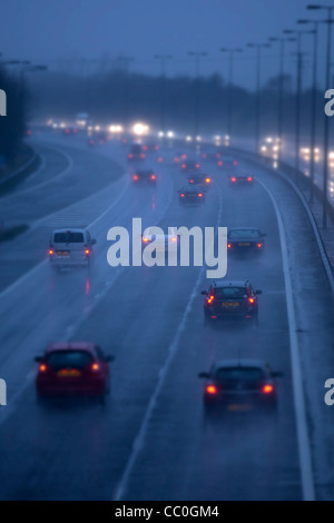 Auto und Verkehr auf einem nassen Abend auf Großbritannien Autobahn zu regnen. Autofahren in gefährlichen winterlichen Bedingungen. Stockfoto