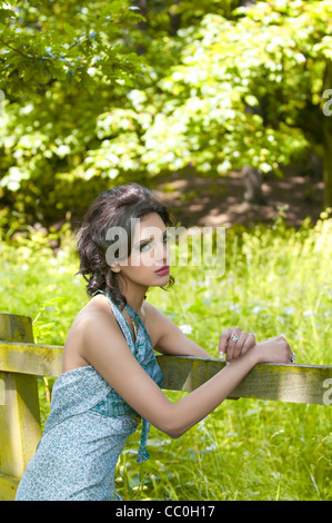 Schöne junge Frau, stützte sich auf einen hölzernen Zaun wegschauen Stockfoto