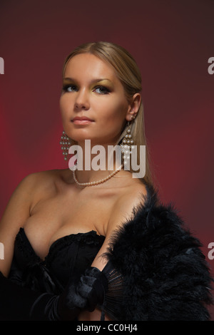 Frau am Maskerade stehend mit Feder Faecher und schwarzes Korsett Stockfoto