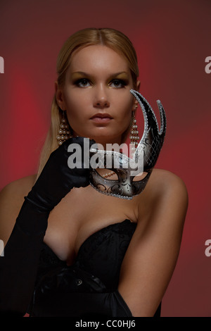 Wunderschöne junge Frau an Maskerade hält silbernen venezianischen Maske Stockfoto