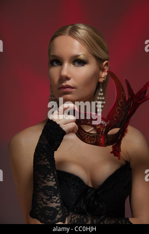 Blonde Frau korsettierten stehend mit Verkleidung Maske Stockfoto