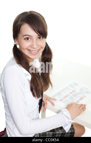 Glücklich Schulmädchen lächelnd und drehen wieder auf dem Schreibtisch zu sitzen Stockfoto