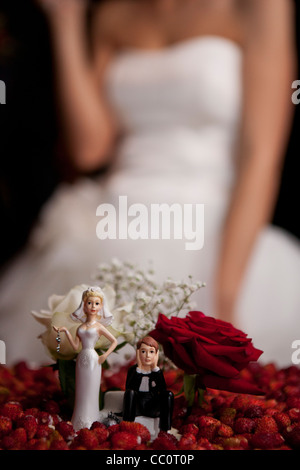 Braut und Bräutigam Figuren auf Hochzeitstorte, mit der Braut hinter Stockfoto