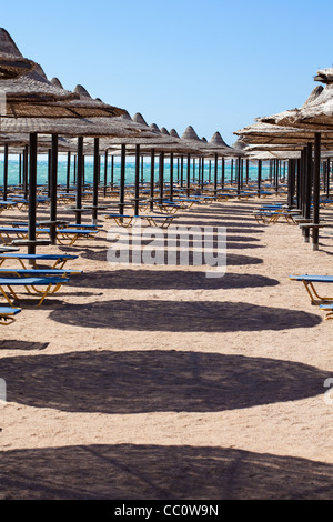 Strand liegen und Sonnenschirme Reihen mit Mittag Schatten Stockfoto