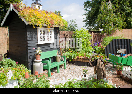 Kleiner Gemüsegarten mit schwarz gemalte Hütte und essbare Grenze. Stockfoto