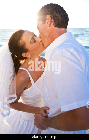 Ein verheiratetes Paar, Braut und Bräutigam, küssen bei Sonnenuntergang an einem wunderschönen tropischen Strand Stockfoto