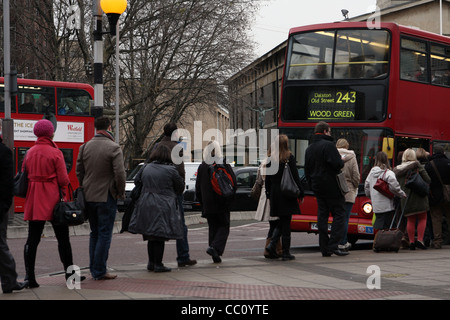 eine Schlange von Menschen warten auf einen roten Londoner Bus an Bord Stockfoto