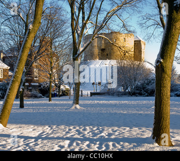 Cliffords Tower in York nach schwerem Schnee, eingerahmt von den Bäumen des Tower Garden. Stockfoto