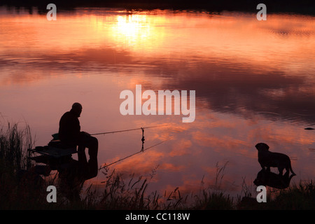 Fischer und Hund am Seeufer in den späten Abend Sonne. Leitrim. Irland Stockfoto