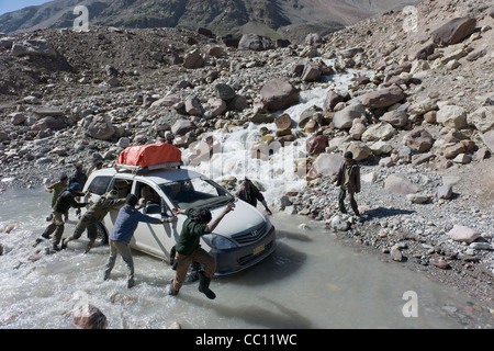 Straßenarbeiter schieben eine gestrandete Touristen-Fahrzeug durch einen Bach an der Manali-Leh Highway, Himachal Pradesh, Indien Stockfoto