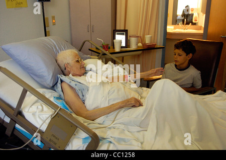 73 Jahre alte Anglo eingehakt mit Sauerstoff erhält Besuch von Enkel die lag sie im Krankenhausbett mit Krebs im Endstadium Stockfoto