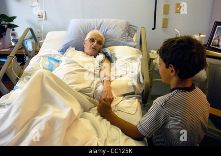 73 Jahre alte Anglo eingehakt mit Sauerstoff erhält Besuch von Enkel die lag sie im Krankenhausbett mit Krebs im Endstadium Stockfoto