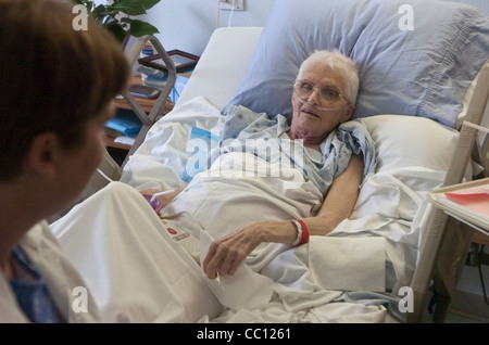 73 Jahre alte Anglo eingehakt mit Sauerstoff erhält Besuch von Enkel die lag sie im Krankenhausbett mit Krebs im Endstadium Stockfoto