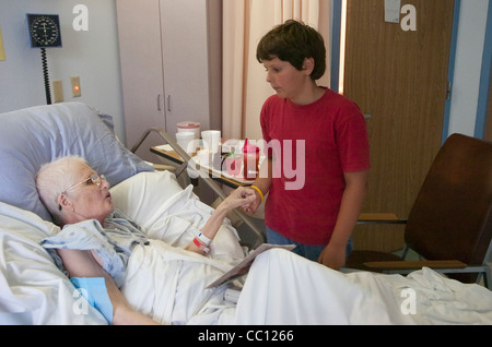 73 Jahre alte Anglo eingehakt mit Sauerstoff erhält Besuch von Enkel die lag sie im Krankenhausbett mit Krebs im Endstadium Stockfoto