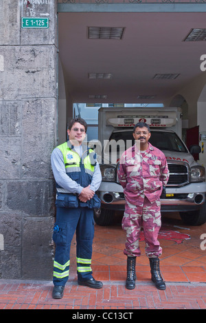 Zwei Männer, ein Feuerwehrmann und ein Sanitäter stellen Sie sich vor ihrer Feuerwache in Quito, Ecuador. Stockfoto