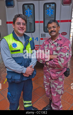 Zwei Männer, ein Feuerwehrmann und ein Sanitäter stellen Sie sich vor ihrer Feuerwache in Quito, Ecuador. Stockfoto