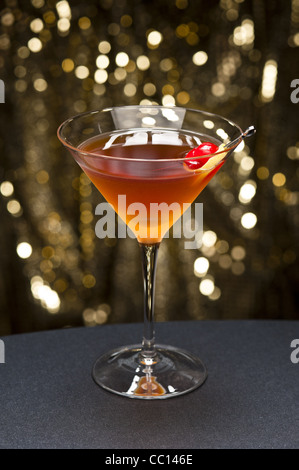 Manhattan-Cocktail, garniert mit einer Kirsche und Zitrone und Gold glitter Boden zurück Stockfoto