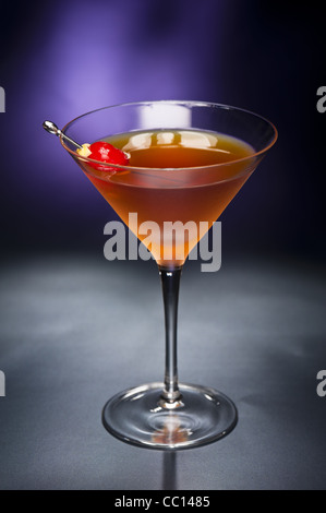 Manhattan-Cocktail, garniert mit einer Kirsche und Zitrone und Gold glitter Boden zurück Stockfoto