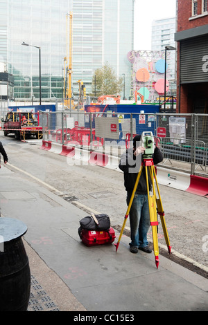 Über eine automatische Nivellierung Tool Landvermesser Umfragen einen Bereich außerhalb der Baustelle, London, UK Stockfoto