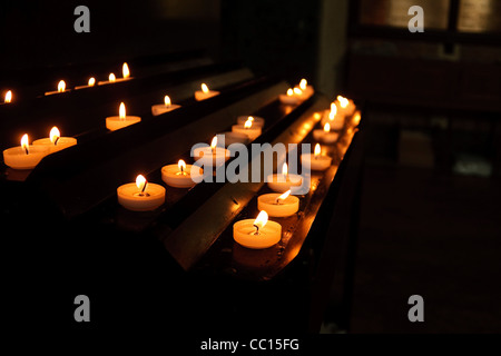 Reihen von weißen Votiv-Kerzen in einer katholischen Kirche Stockfoto