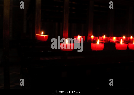 Reihen von roten Votiv-Kerzen in einer katholischen Kirche Stockfoto