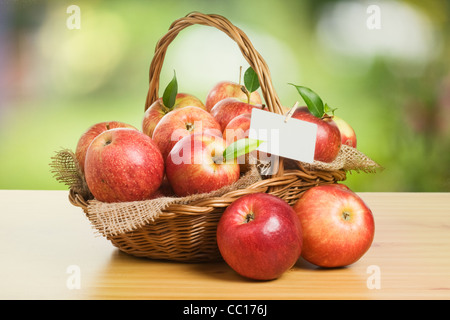 Jonagold Äpfel in einem Korb auf Holztisch mit einer leeren Karte Stockfoto