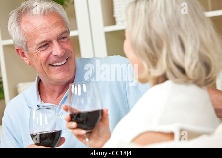 Ältere Mann und Frau Brautpaar zu Hause lächelnd und trinken Wein zusammensitzen Stockfoto