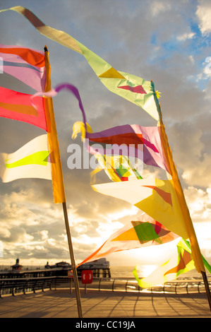 Bunte Fahnen im Wind flattern auf der Promenade in Blackpool bei Sonnenuntergang Stockfoto