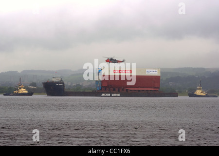 Bei grauenhafter Witterung führt Anchor Marines, Amt Trader, einen Teil des neuen Flugzeugträgers der Royal Navy entlang des Flusses Clyde, Schottland, Großbritannien Stockfoto