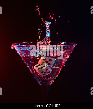 Würfel fallen in ein Glas mit Martini. Stockfoto