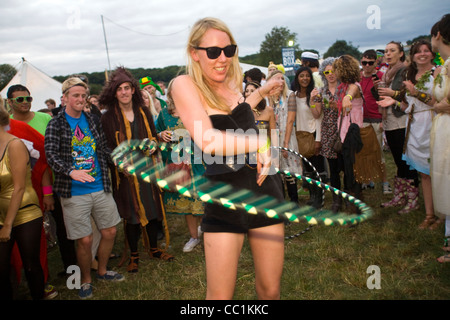 Eine Frau Hola Reifen und tanzt in einem Feld zu einem mobilen Soundsystem beim Standon Calling Festival in Hertfordshire Stockfoto