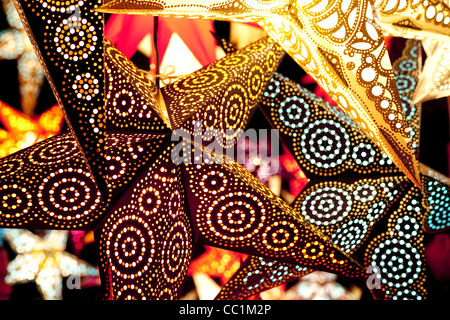 Hell, farbenfroh und dynamisch beleuchtet Papier Sterne hängen in einen Weihnachtsmarkt in München. Stockfoto