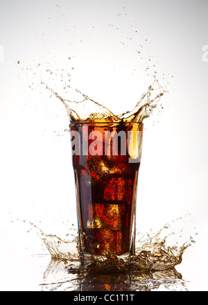 Ice Cube Droped in Glas Cola und Cola Spritzen Stockfoto