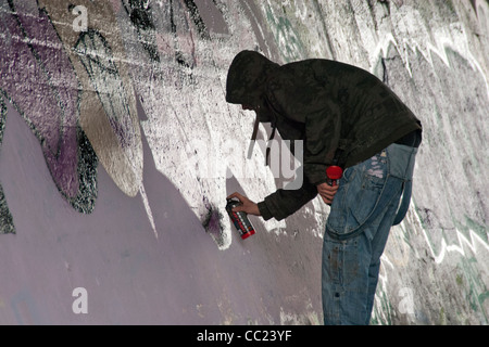 Tagging - Kapuzen-jungen Mann mit Sprühfarbe Kanister Malerei Graffiti, West-London, UK Stockfoto