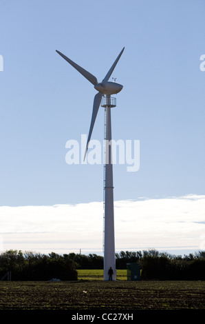 Ein einsamer Windkraftanlage Silhouette gegen einen blauen Himmel mit der Sonne hinter der Nabe Stockfoto