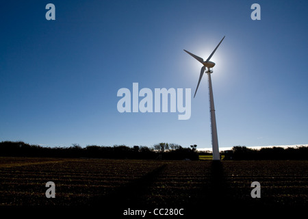 Ein einsamer Windkraftanlage Silhouette gegen einen blauen Himmel mit der Sonne hinter der Nabe Stockfoto