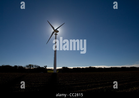 Ein einsamer Windkraftanlage Silhouette gegen einen blauen Himmel mit der Sonne hinter der Nabe Stockfoto