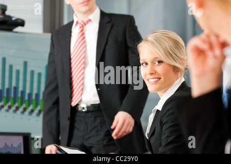 Business - Präsentation im Team; eine weibliche Kollegin steht auf dem Flipchart, eine junge Frau sucht in die cam Stockfoto